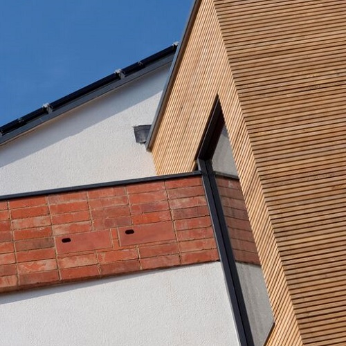 The outside of zero carbon house, Birmingham showing homes for two birds within the red bricks