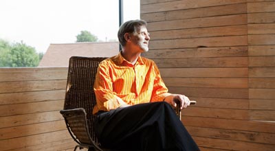 John Christophers, architect of zero carbon house, Birmingham sits in the studio in an orange shirt