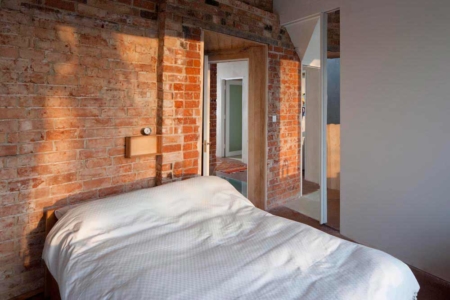 Bedroom in zero carbon house Birmingham with white duvet and sunlight on original bricks