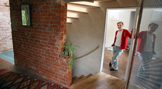 John Christophers on the first floor of zero carbon house Birmingham with light through the stairs