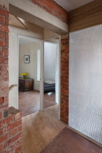 View into bedroom at zero carbon house, Birmingham with flowers on chest and Mykon wall to reflect light