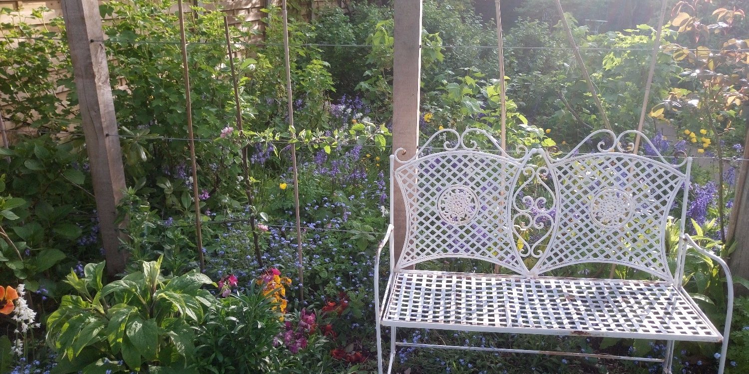 White seat in garden of zero carbon house Birmingham with sunshine and flowers